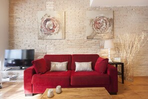 A living room with a red sofa, a TV, and abstract art on the wall.