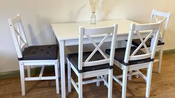 A white dining table with four chairs, each with a cushioned seat and backrest.