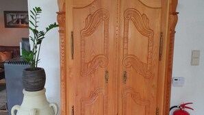 Et træskab med detaljeret udskæring, en vase med en plante, og en brandslukker.