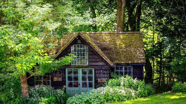 Eine rustikale Holzhütte, umgeben von üppigem Grün und einem gepflegten Garten.
