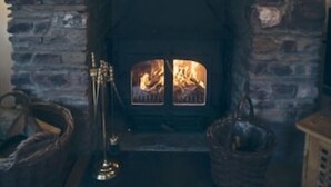 Ein Steinkamin mit Feuer, umgeben von Steinwänden.