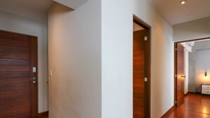 A hallway with wooden flooring, a wooden door, and a white wall. - w*| Lush 2BR w/AC Near Kennedy Park in Miraflores (Miraflores)