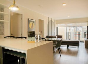 A modern kitchen with a large island, dining area with chairs, and a view of the city through large windows.