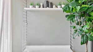 Un intérieur moderne avec deux étagères blanches, une lampe suspendue et une plante en pot.