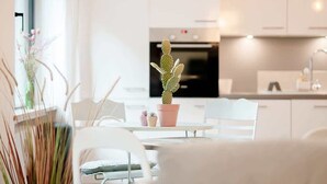 A modern kitchen with white cabinets, a black oven, and a dining area with a table and chairs.