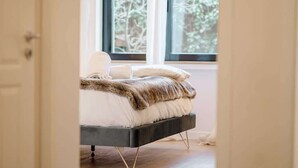A bed with a fur throw, a white pillow, and a window with a view of trees.