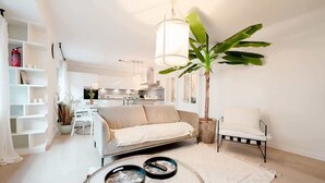 A modern living room with a sofa, a chair, a coffee table, and a large plant.