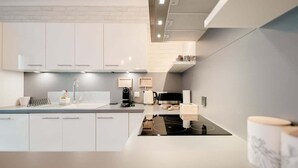 A modern kitchen with white cabinetry, a black countertop, and a built-in stove.
