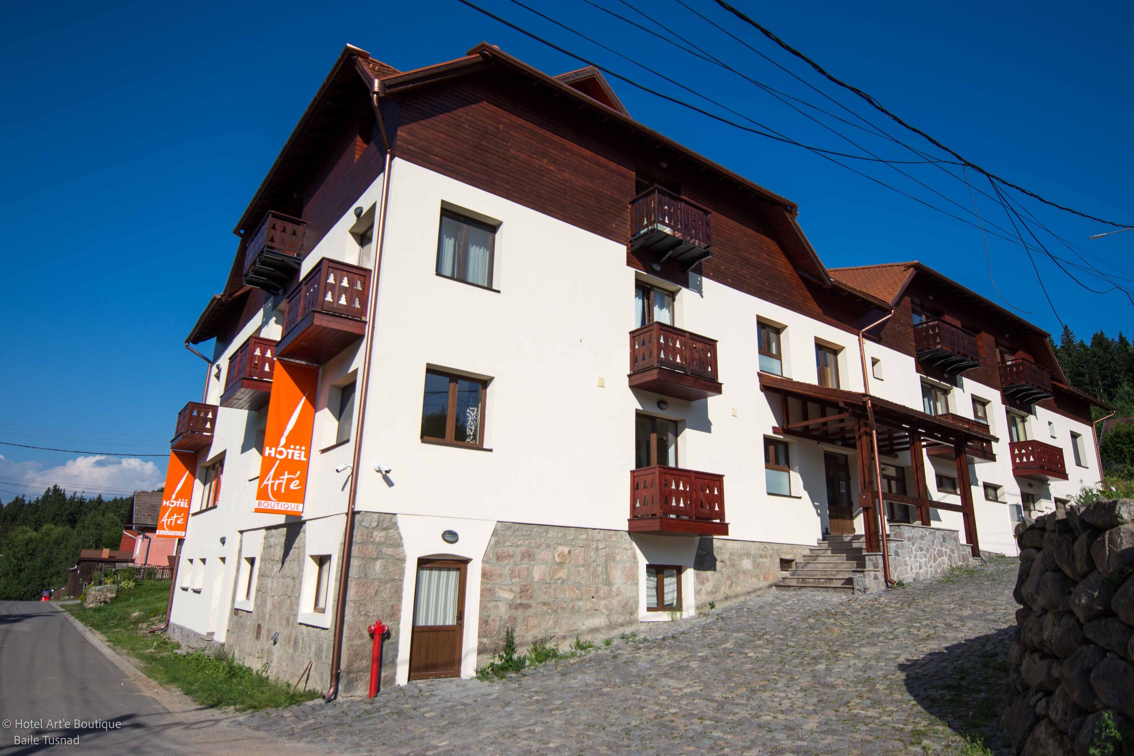 Um hotel com vários andares, varandas, base de pedra e entrada em pedra.