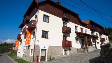 Um hotel com vários andares, varandas, base de pedra e entrada em pedra.