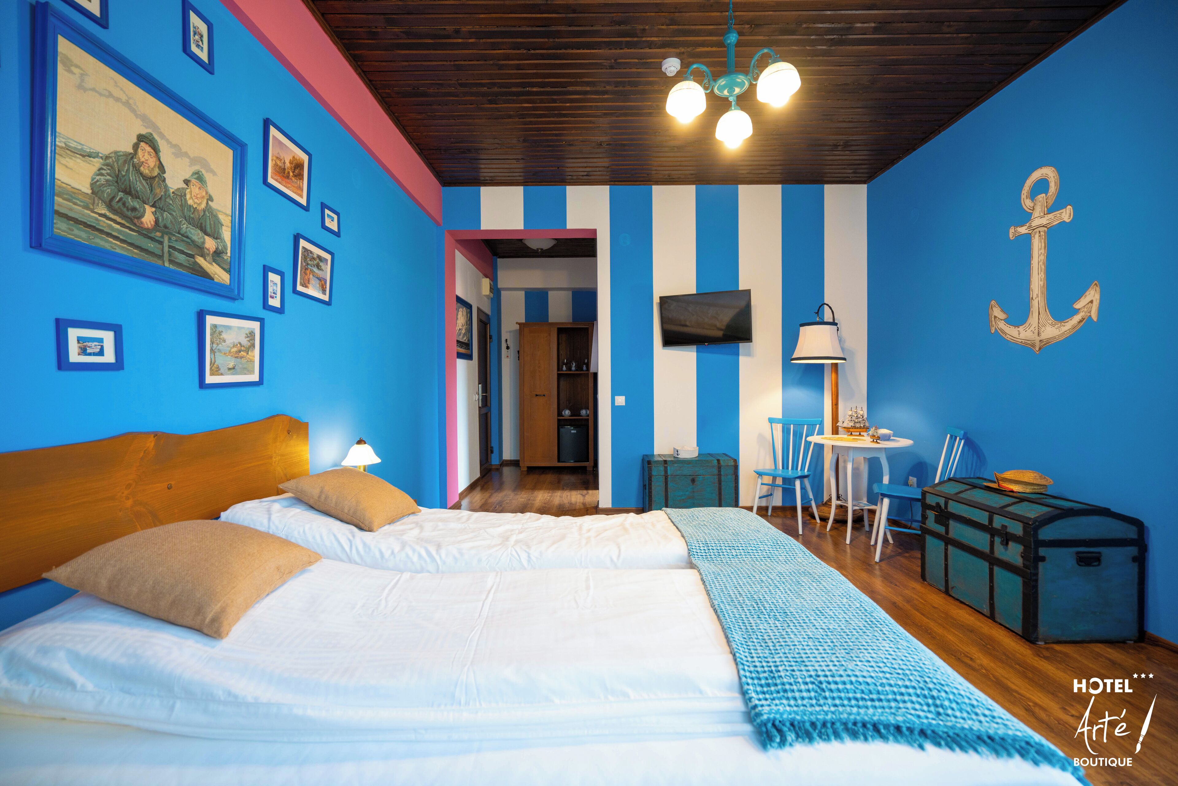 A hotel room with a large bed, a desk, a chair, a lamp, and a television.