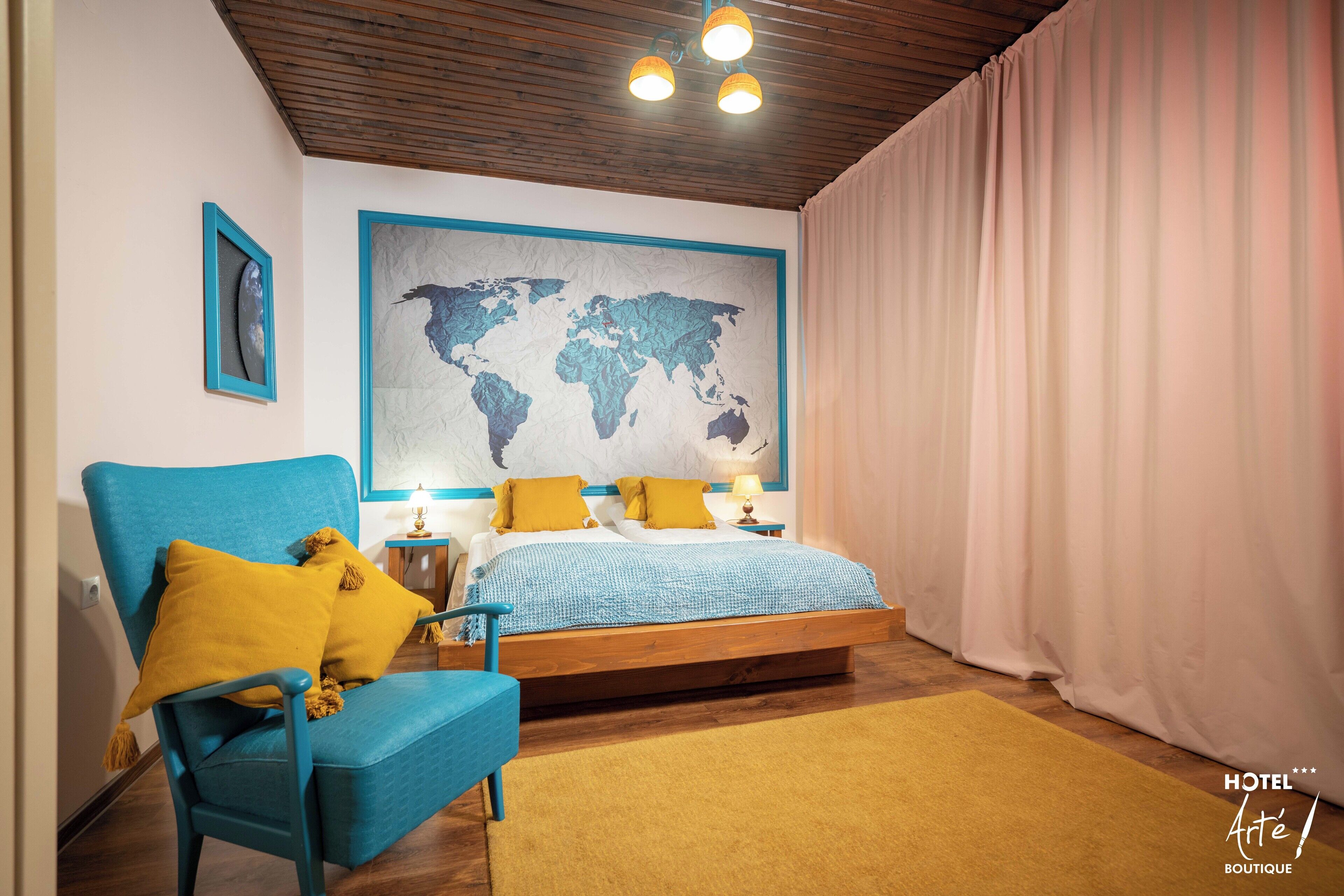 Un dormitorio con una cama, un sillón azul, un mapa del mundo en la pared y techo de madera.