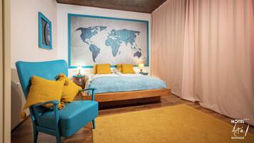 Un dormitorio con una cama, un sillón azul, un mapa del mundo en la pared y techo de madera.
