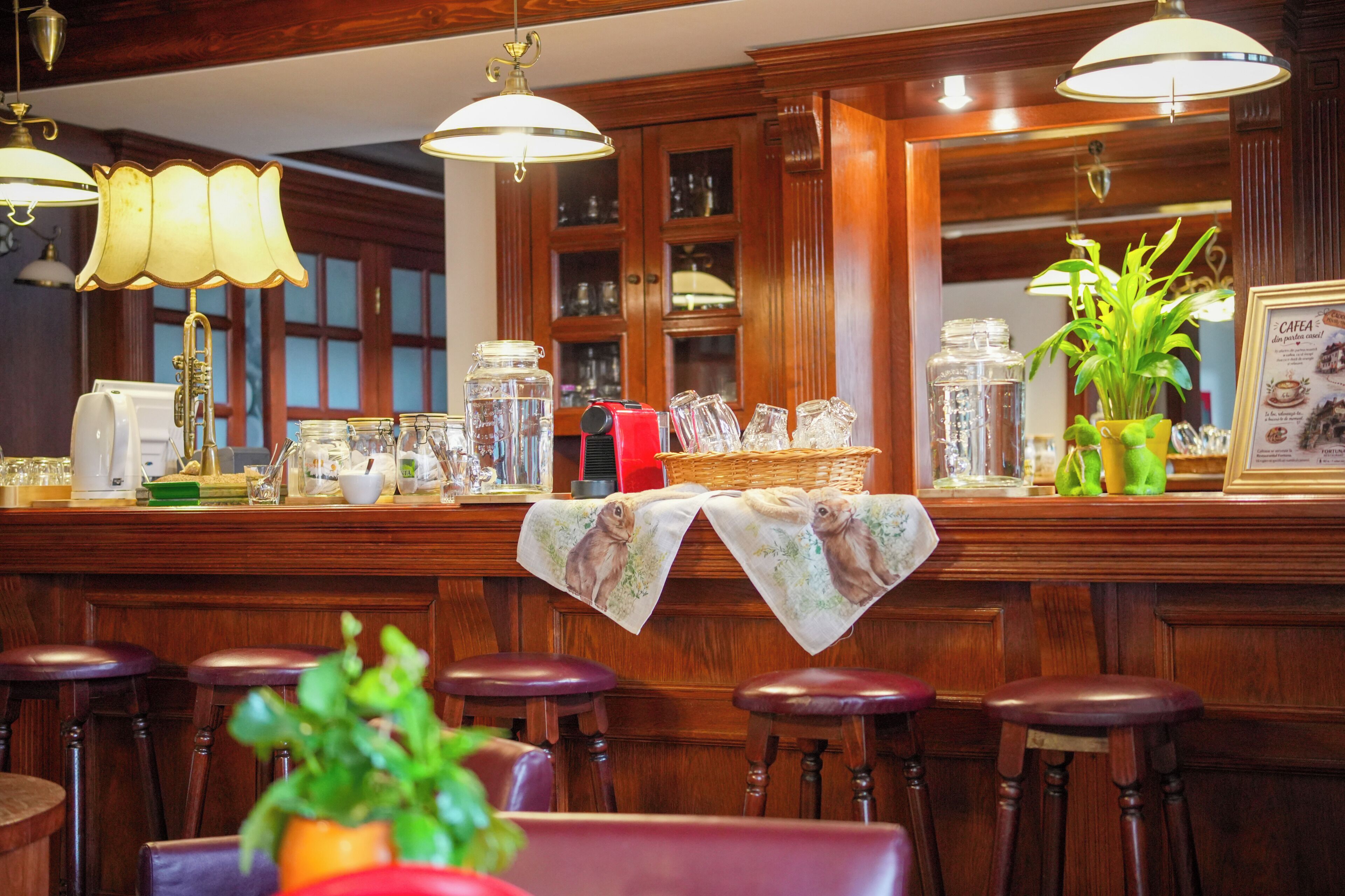 A bar area with wooden bar stools, a counter with various glassware, and a menu board.