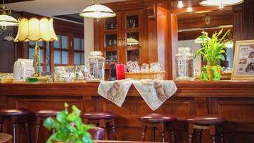 A bar area with wooden bar stools, a counter with various glassware, and a menu board.