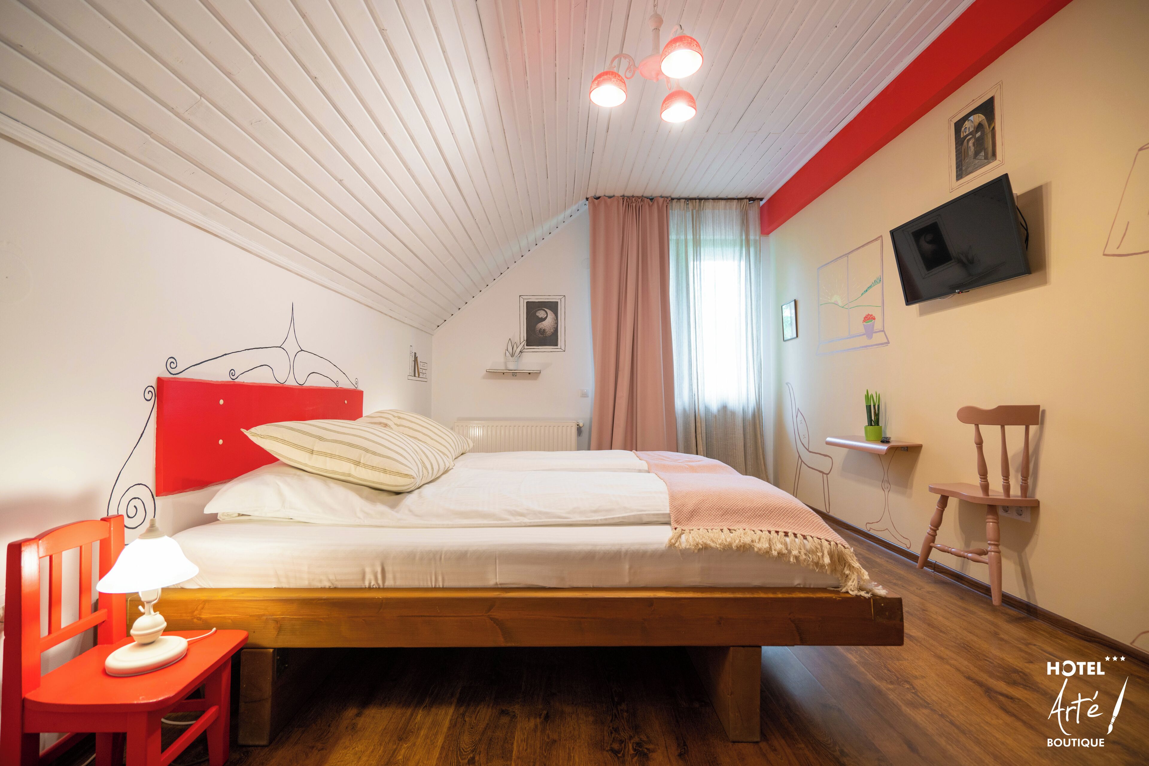 A bedroom with a wooden bed, a red chair, a bedside table with a lamp, a television on the wall, and a small shelf with a plant.