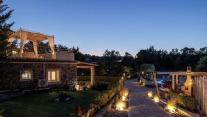 A well-lit outdoor area with a stone pathway, a covered seating area, and a pool. - Villa St. Nicholas House, Family Friendly, Large Heated Pool, 300m to the beach. (Corfu)