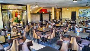 Un espaiós restaurant amb diverses taules i cadires, una escala al fons i un quadre gran a la pared.