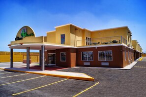 A hotel with a yellow facade, a covered entrance, and a sign with a logo and text. - Los Cedros Hotel Inn Torreon (Torreón)