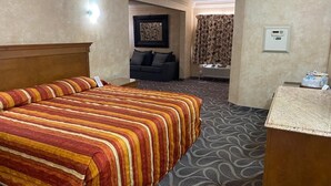 Habitació d'hotel amb un llit gran, un sofà, una taula de treball i un bany.