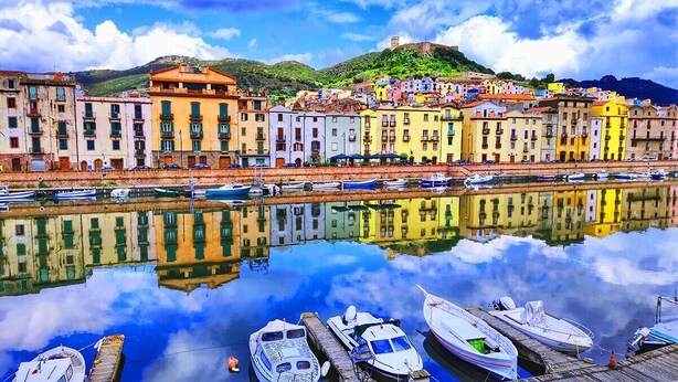 A waterfront with colorful buildings and boats docked along the shore. - "Loft delle Concerie: History and Comfort in the Heart of Bosa" (Bosa)