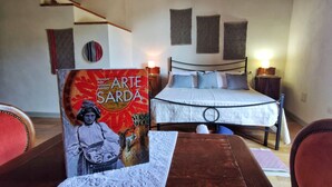 A bedroom with a bed, a table, and a chair. There is a book titled "Arte Sarda" on the table. - "Loft delle Concerie: History and Comfort in the Heart of Bosa" (Bosa)
