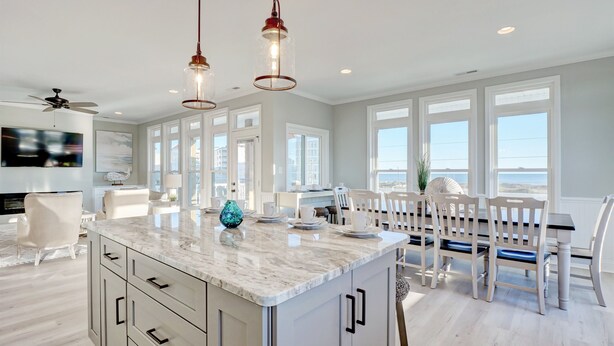 A spacious kitchen with a marble island, white cabinetry, and pendant lighting. - Luxurious 7BR Beach Home w/ Ocean Views, Pool, Hot tub, and Elevator (North Topsail Beach)