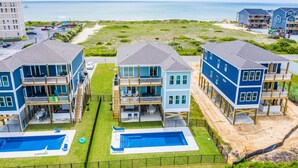 A beachfront property with multiple two-story buildings, a swimming pool, and a beach view. - Luxurious 7BR Beach Home w/ Ocean Views, Pool, Hot tub, and Elevator (North Topsail Beach)