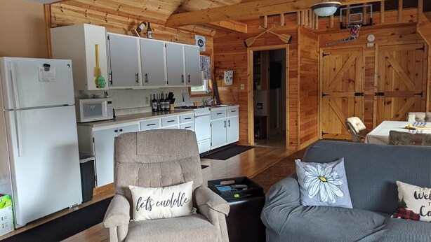 A cozy cabin interior with a kitchenette, a sofa, and a chair. - Remote cabin - quick access to all the U.P. has to offer. (Germfask)