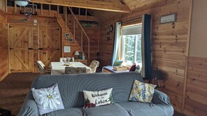 A cabin interior with a couch, a table, and a window. - Remote cabin - quick access to all the U.P. has to offer. (Germfask)