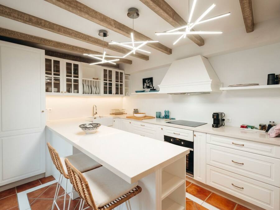 A modern kitchen with white cabinetry, a central island, and a pendant light fixture.
