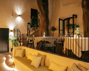 An indoor dining area with tables and chairs, a staircase, and a sofa with cushions. - La Fonda Heritage Hotel Relais &Châteaux (Marbella)