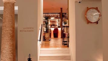 A staircase leading to a bar area with a clock on the wall.