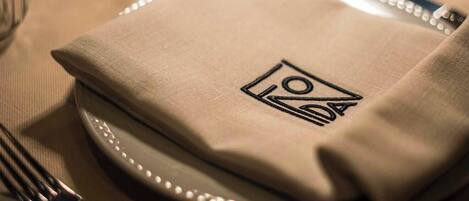 A neatly folded napkin with a logo on a table set for dining.