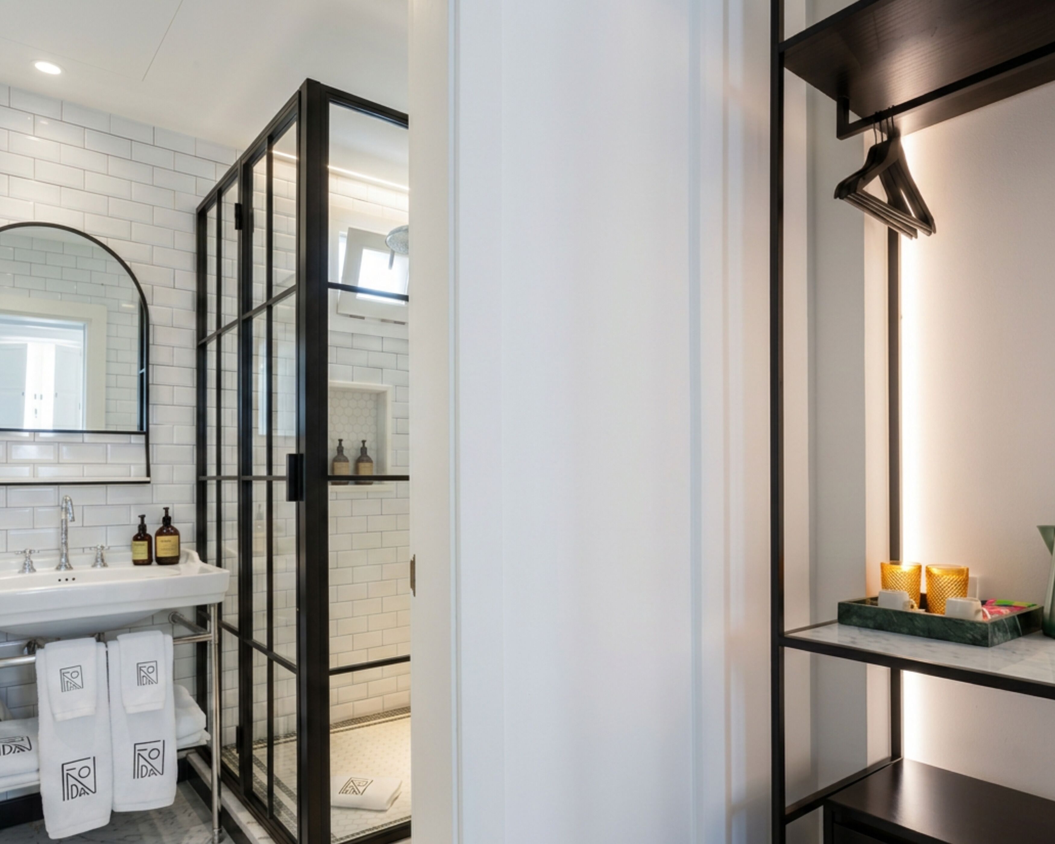 Een moderne badkamer met een wit wastafelmeubel, spiegel en een douchecabine met een zwarte omlijsting.