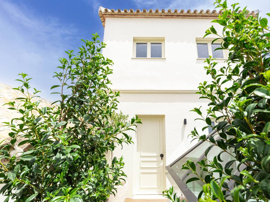 A two-story building with a white facade, a door, and windows.