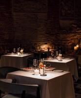 A restaurant with tables set for dining, featuring candles and floral centerpieces.