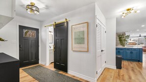 A modern kitchen with blue cabinets, a black door, and a framed artwork on the wall. - Lake and marina 5 minutes away Large family friendly Cozy home with country feel (Leesburg)