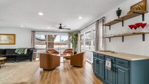 A modern living room with a sofa, chairs, a coffee table, and a kitchen area with shelves and cabinets. - Lake and marina 5 minutes away Large family friendly Cozy home with country feel (Leesburg)