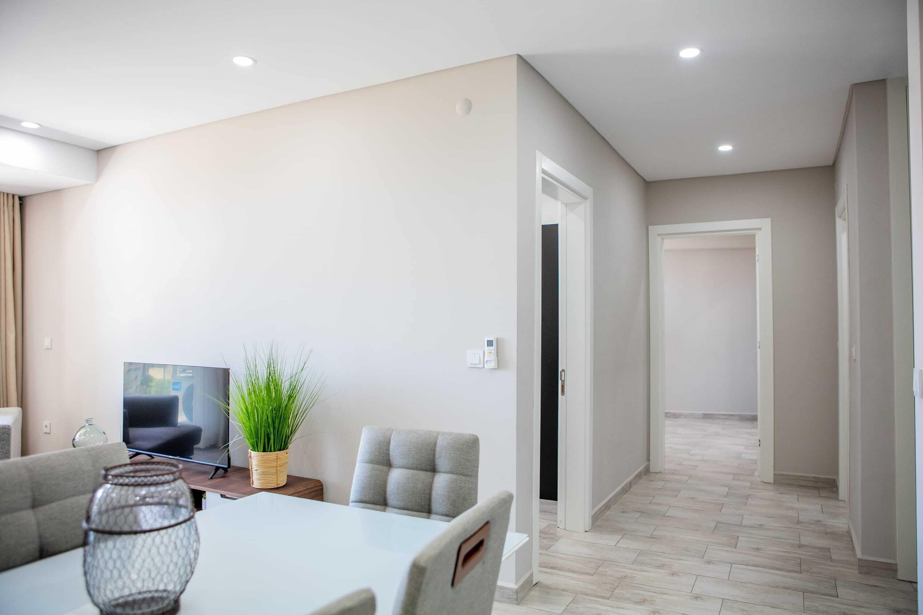 Una sala de estar moderna con televisor, sofá, mesa de comedor y sillas.