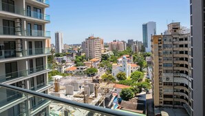 A high-rise building with multiple balconies and a view of a cityscape including various buildings and construction sites. - Maison Moz - Polana Plaza IV (Maputo)