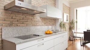 Una cocina moderna con encimera de granito, campana extractora de acero inoxidable y armarios blancos.