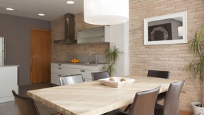 Una cocina moderna con pared de ladrillo, puerta de madera y comedor con mesa y sillas.
