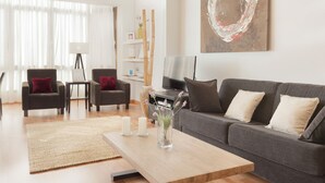 Una sala de estar moderna con un sofá, sillas, una mesa de centro y un televisor.