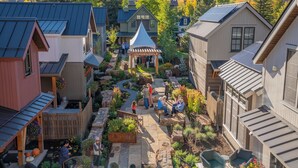 Une cour avec un belvédère, entourée de bâtiments dotés de panneaux solaires, et un paysage montagneux en arrière-plan.