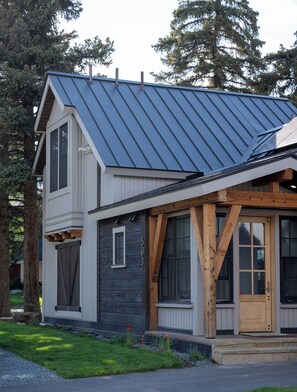 A two-story house with a metal roof, wooden beams, and a front door.