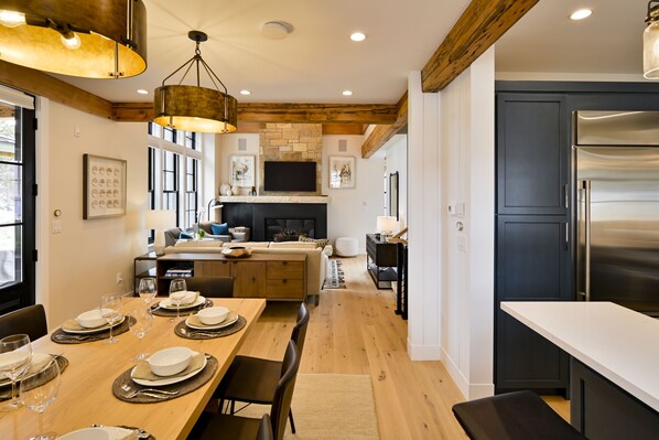 A modern kitchen with a large island, dark cabinetry, and a stainless steel refrigerator. - Mariposa at Academy Place (Crested Butte)