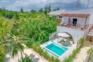 A white villa with a pool, surrounded by lush greenery and palm trees. - Alma Boutique Hotel (Jambiani)