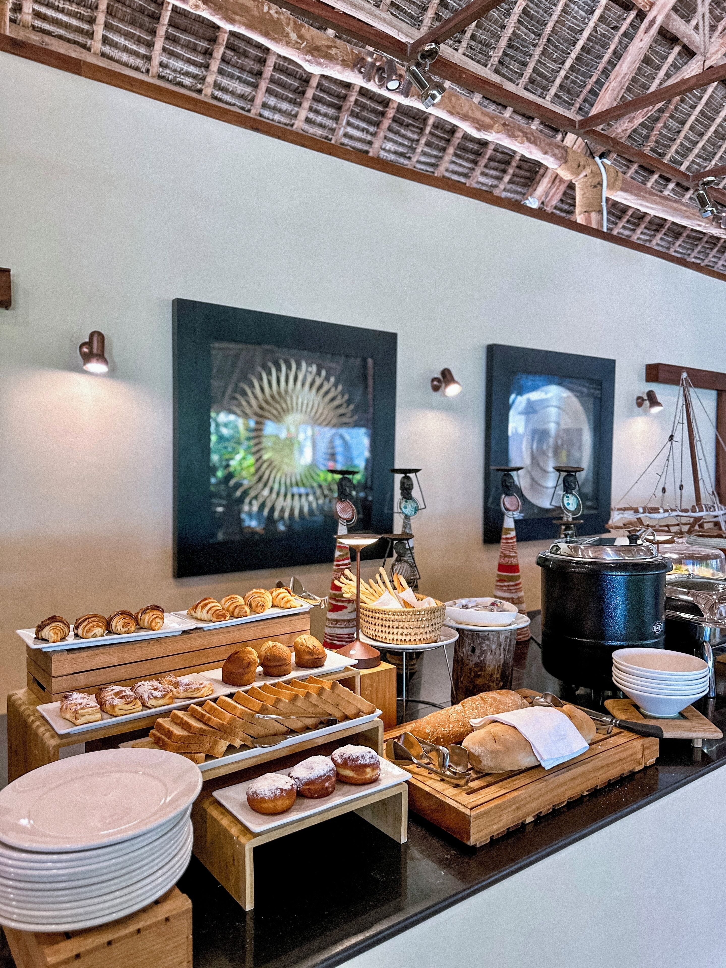 Un bufé de desayuno con diversos pasteles, pan y platos.