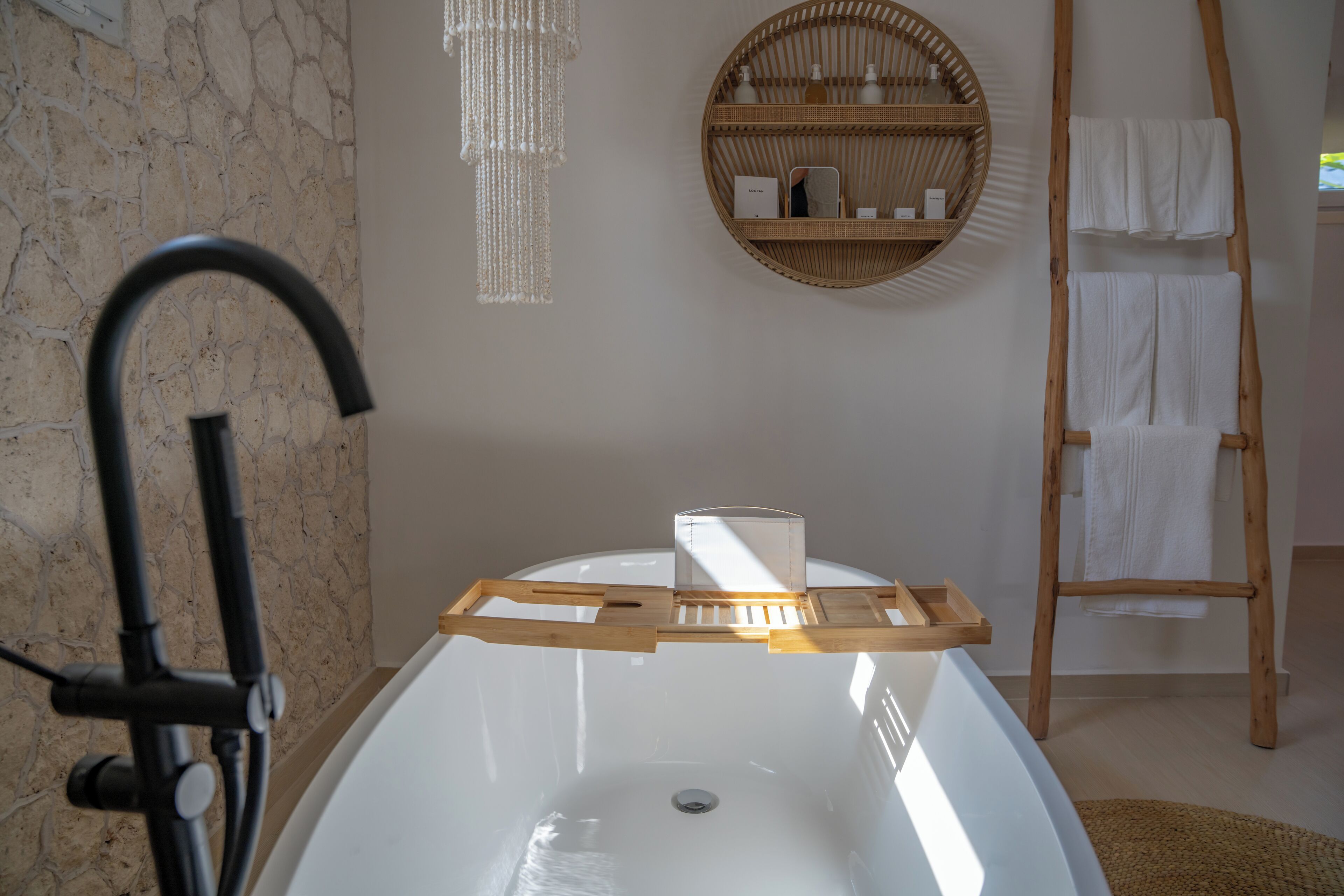 Ein Badezimmer mit einer Badewanne, einer Holzleiter, einem runden Korbsockel und einer hängenden Leuchte.